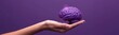 © kramynina - Someone holding a purple brain shape with a purple background, copy space
