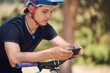 © Michael Cunningham/peopleimages.com - Fitness, bicycle and man with phone online for training, adventure and exercise in nature. Sports, cycling and happy person on mountain bike with smartphone for navigation, website and health app