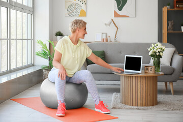 Sticker - Sporty mature woman with laptop training at home