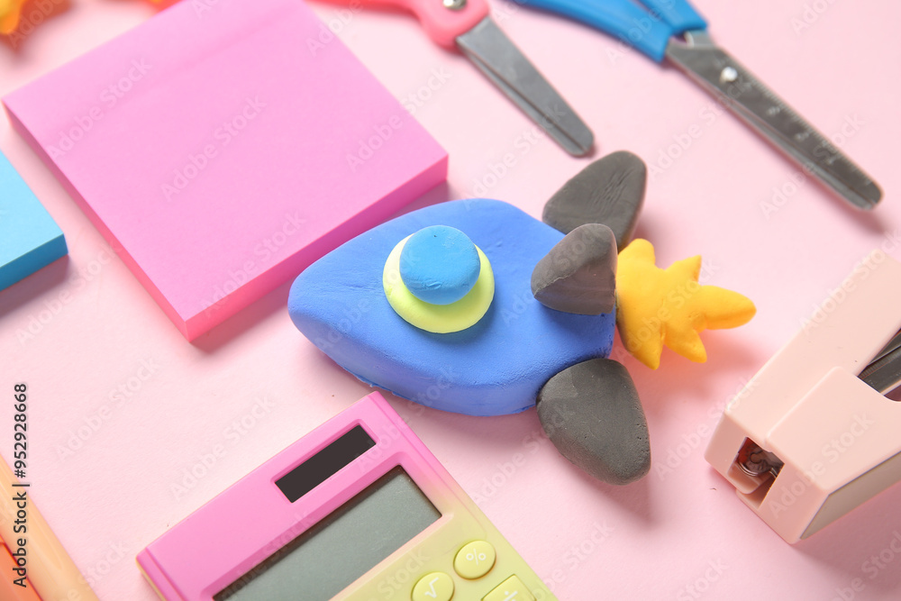 Rocket made of plasticine with different stationery on pink background