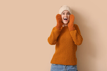 young woman in winter clothes on beige background