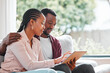 © peopleimages.com - People, black couple and smile with tablet on sofa at home with browsing internet for house insurance options. Family, relationship and happy or satisfied on website for life policy and funeral cover