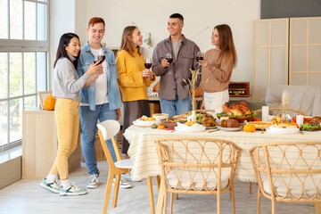 Wall Mural - Group of young friends with punch having dinner on Thanksgiving Day