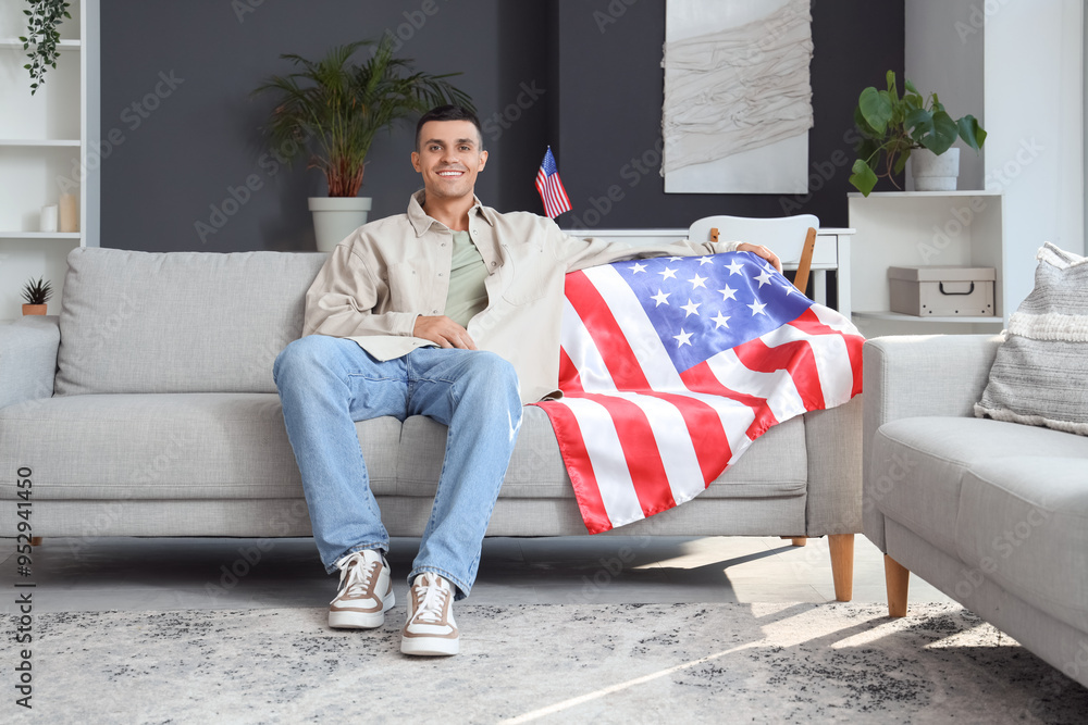Young man with USA flag sitting on sofa at home. Veterans Day celebration