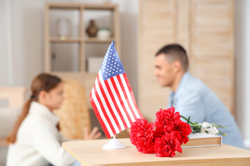 Wall Mural - USA flag with carnation flowers on table in room, closeup. Veterans Day celebration