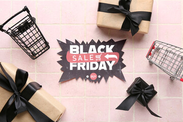 Poster - Greeting card with text BLACK FRIDAY SALE, gift boxes and shopping cart on pink table