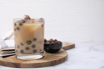 Wall Mural - Tasty milk bubble tea in glass, tapioca pearls and straws on white marble table, space for text