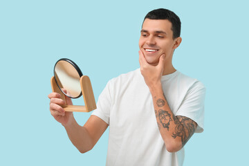 Sticker - Handsome young man with mirror after shaving on blue background