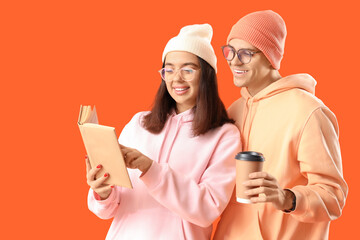 Sticker - Young couple in eyeglasses with coffee cup and book on orange background