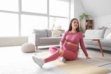 Wall Mural - Sporty pregnant woman sitting on fitness mat at home