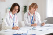 © Pixel-Shot - Female medical interns studying at table in clinic