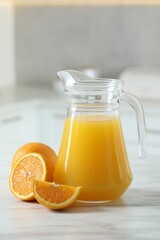 Sticker - Tasty orange juice in jug and citrus fruits on white marble table