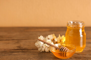 Bowl and jar of sweet honey with acacia flowers on wooden table