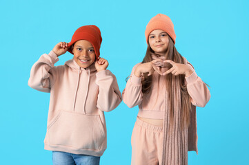 Sticker - Cute little happy children in winter clothes showing heart gesture on blue background