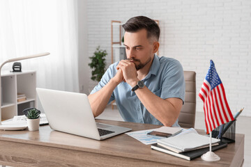 Poster - Handsome young man with laptop and flag of USA working at table in office