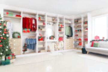 Poster - Modern wardrobe with stylish festive clothes, gift boxes and Christmas tree, blurred view