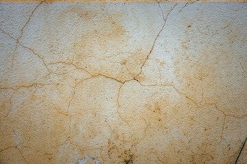 Wall Mural - A wall with cracks and holes in it. The wall is made of concrete and has a rough texture