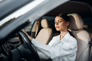 Wall Mural - Woman, driver, car a woman is seated in the driver's seat of a car, both hands on the steering wheel, and looking at the camera confidently