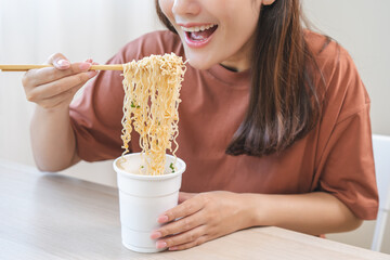 Happy temptation, attractive asian young student woman, cute girl using chopsticks eating instant ramen, noodles soup from a cup, cooking meal fast food lifestyle of traditional japanese person.