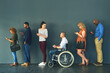 © TamJam/peopleimages.com - Hiring, inclusive and job interview with row of people in studio on gray background for opportunity. Diversity, human resources or recruitment and man with disability in wheelchair for equality