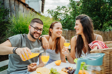 Group of three friends or family having picnic in backyard or garden