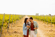 © BGStock72 - A joyful couple enjoying wine tasting together in a sunny vineyard during the golden hour, surrounded by lush green grapevines