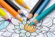 © Татьяна Евдокимова - Several sharpened colored pencils pointing at a partially colored mandala design in an adult coloring book