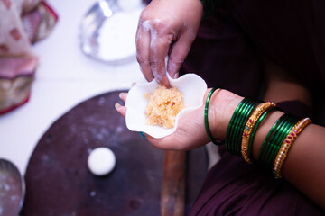 Woman making sweet rice modak stuffed with grated coconut and jaggery