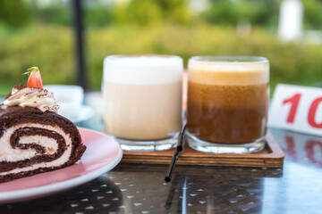 A plate of cake and two glasses of coffee sit on a table