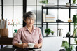 © Fahng - Mature asian business woman drinking coffee and thinking about the strategy of new startup while looking out the window in modern office. copy space