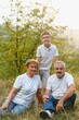© Serhii - Grandparents with they grandson. They playing on meadow and joying in sunset