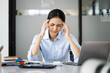© NAMPIX - Young asian woman hand touching her head, feeling depressed stress headache be tired from working with laptop a long time, office syndrome.