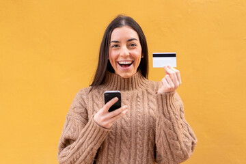 Poster - Young brunette woman at outdoors buying with the mobile with a credit card