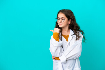 Wall Mural - Little doctor girl isolated on blue background pointing to the side to present a product