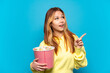 © luismolinero - Teenager girl holding popcorns over isolated blue background intending to realizes the solution while lifting a finger up