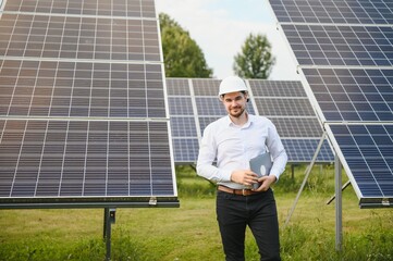 Poster - man in white shirt standing near photovoltaic panels on sunny day in countryside