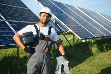 Wall Mural - An Indian worker in uniform and with tools works on a solar panel farm