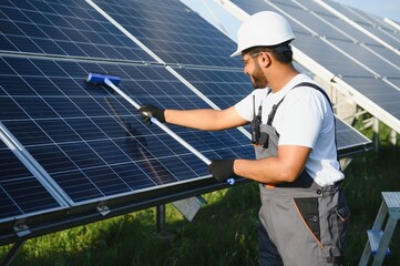 Canvas Print - Indian handyman cleaning solar panels form dust and dirt