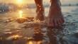 © ProPhotos - Close-up of attractive bare feet on wet sand at a beach resort with crashing waves in the background and golden sunset light creating a serene atmosphere.