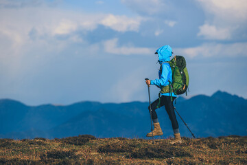 Wall Mural - Woman hiking on sunset high altitude mountain top