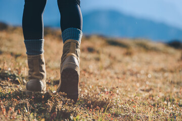 Wall Mural - Hiker legs wearing leather boots hiking on high altitude mountain top