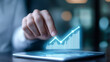 © enterdigital - A close-up of a hand interacting with a digital tablet displaying a rising graph, symbolizing growth and achievement in business.