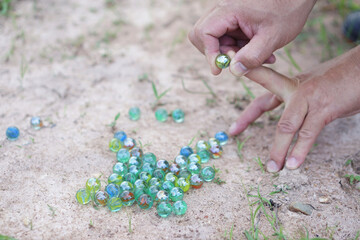 Closeup hand holds round small marble balls to play games. Concept, traditional childen play toy. Recreation activity to make concentrate for kids, fun and competition games            