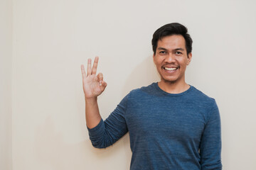 Adult Southeast Asian man  showing excited face expression while giving two OK finger sign,  positive emotion,  copy space.