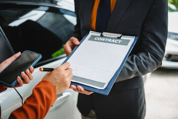 Wall Mural - Car seller agent signs a car insurance agreement with salesman. The document outlines vehicle policy, premium, rental terms, with contract paper finalized using car insurance claim mobile phone.