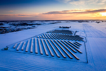 Snowy photovoltaic farm in winter at sunset, aerial view