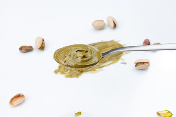 Pistachio paste (cream) in spoon isolated on white background. Smears of green butter (pistachio syrup drizzle) isolated on white