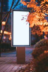 Poster - A large white billboard sits in front of a tree with orange leaves. The billboard is empty, but it is illuminated by the streetlights, creating a sense of mystery and intrigue