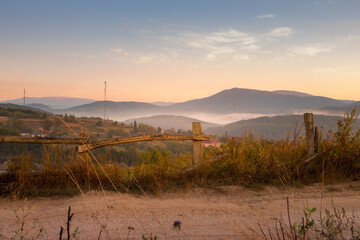 Poster - A Serene Sunrise Casting Golden Light Over Rolling Hills and Fences Across the Horizon