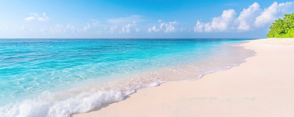 Gorgeous white sand beach with peaceful,rolling waves of the turquoise ocean on a sunny day with white clouds in the blue sky in the backdrop.